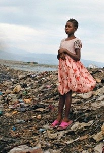 A young girl stands amidst garbage in Cite Soleil, a densely populated slum in Port au Prince, Haiti, April 16, 2008. Hunger bashed in the front gate of Haiti?s presidential palace. Hunger poured onto the streets, burning tires and taking on soldiers and police. Hunger sent the country's prime minister packing. Haiti?s hunger, that burn in the belly that so many in the country feel, has become fiercer than ever in recent days as global food prices spiral out of reach, spiking as much as 45 percent since the end of 2006 and turning Haitian staples such as beans, corn and rice into closely guarded treasures. (Tyler Hicks/The New York Times)